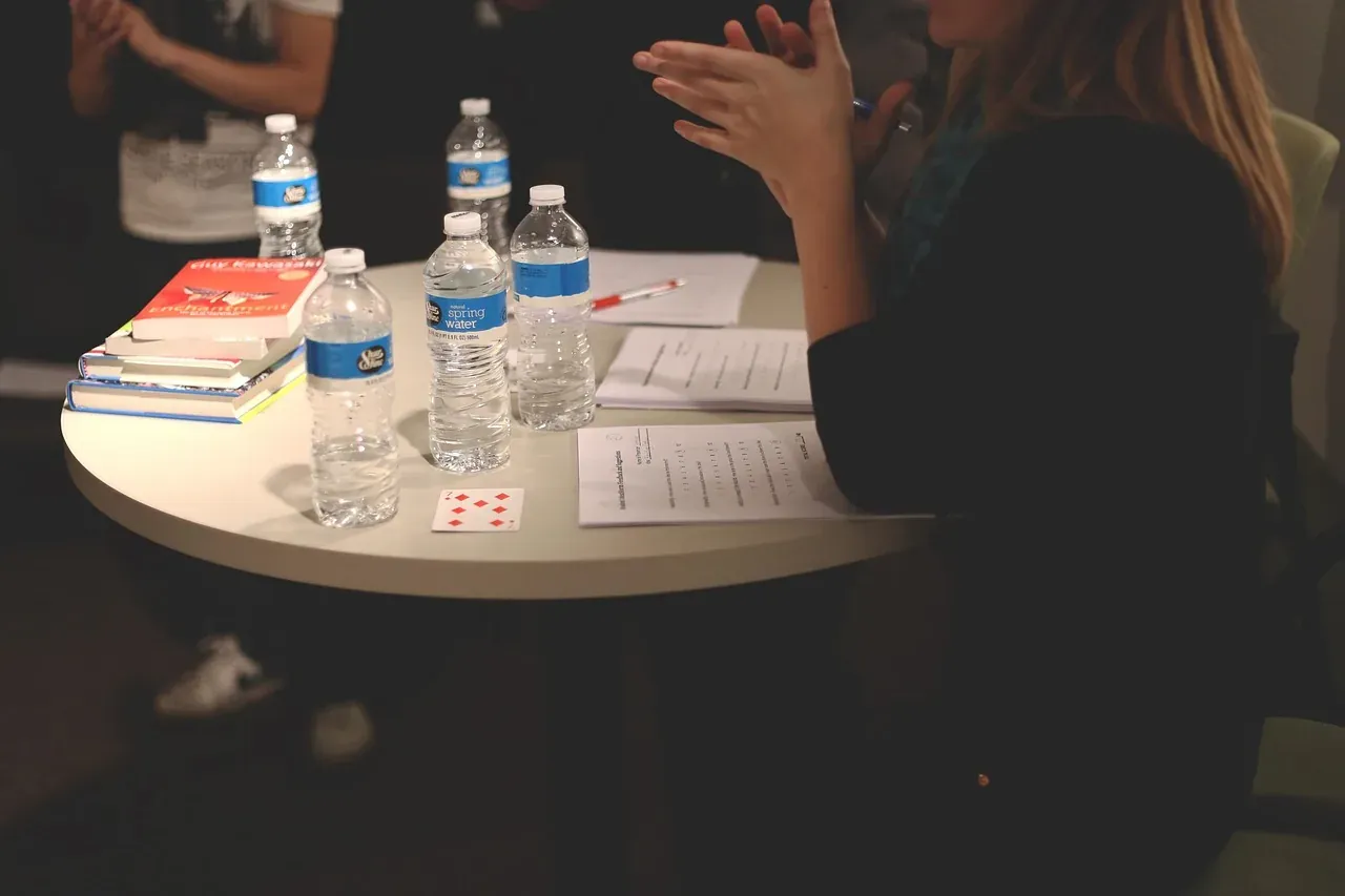 Colleagues talking around a round meeting table with notes and water