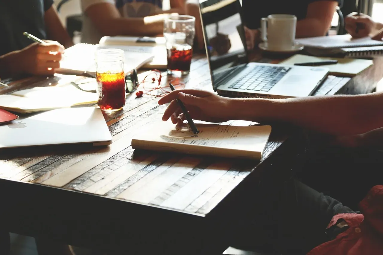 Colleagues working through notes and laptops around a café table