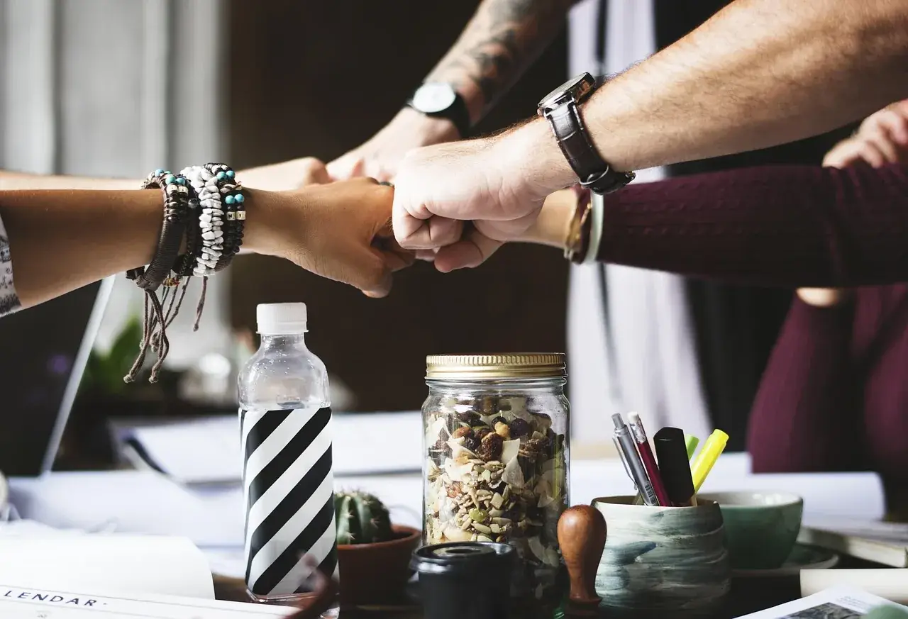 Colleagues joining fists over a desk in a show of teamwork