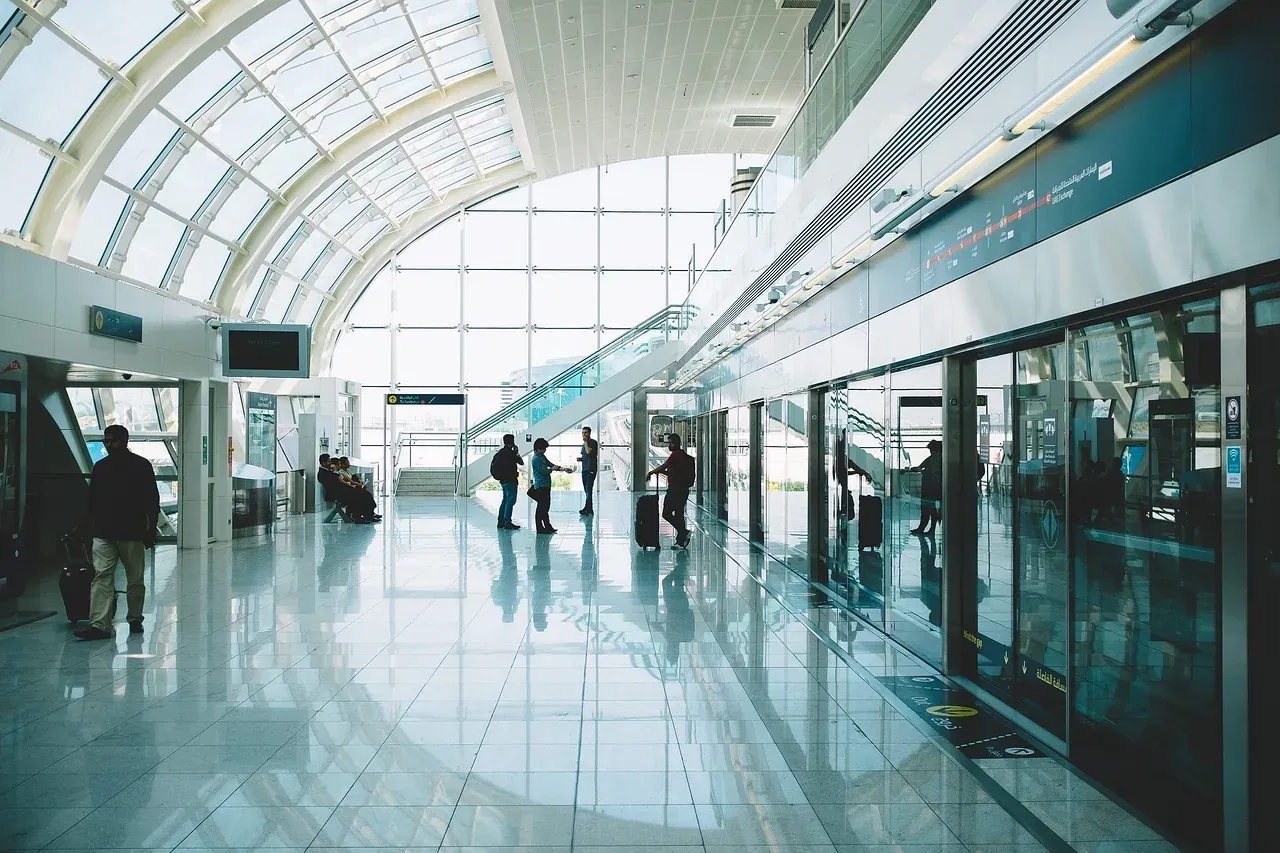 Travellers walking through a bright, glass-roofed station concourse