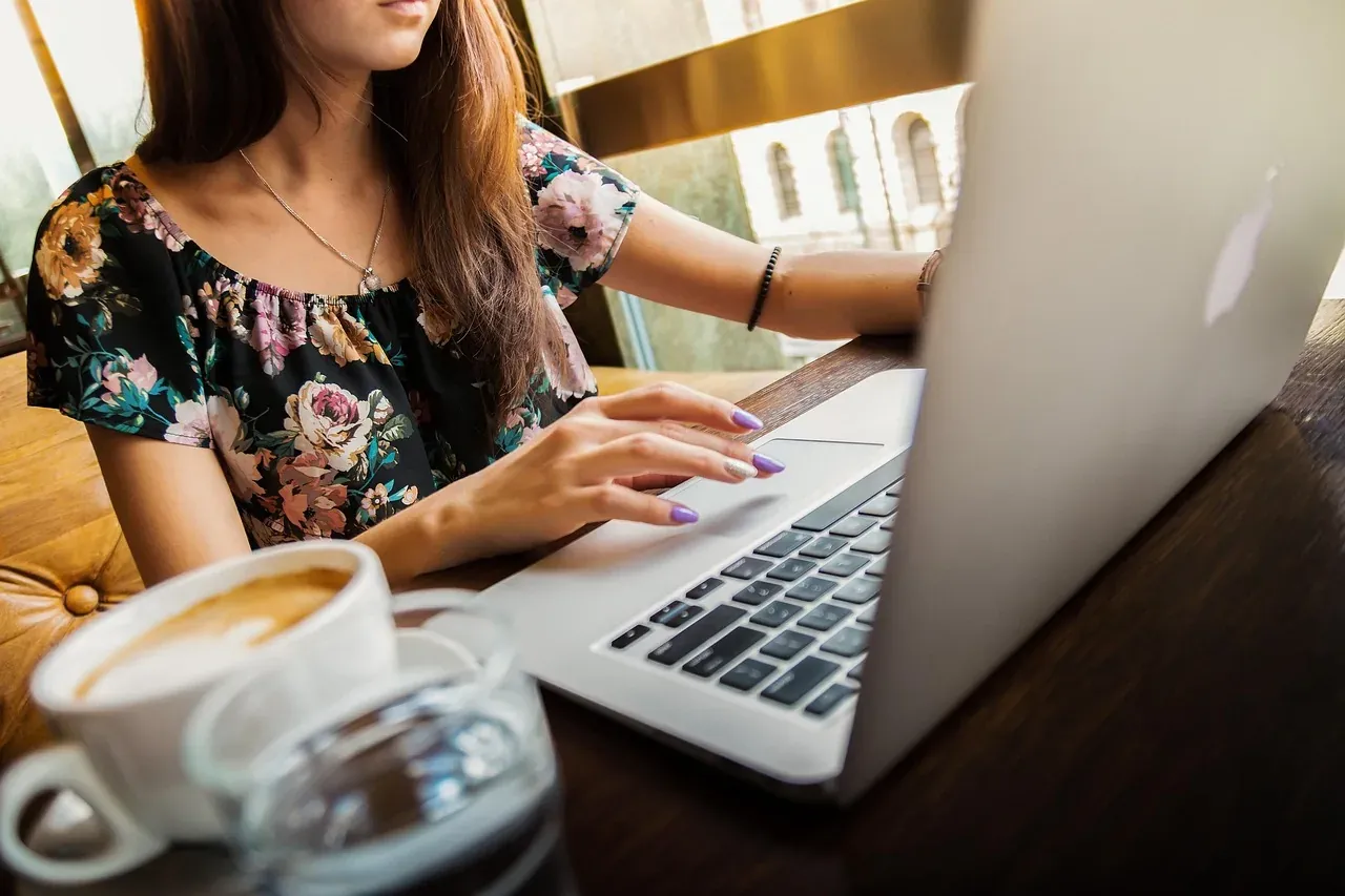 Woman working on a laptop at a café table with coffee